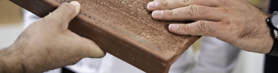 Hands touching surface structure of roof- and façade clay tile "Urban"
